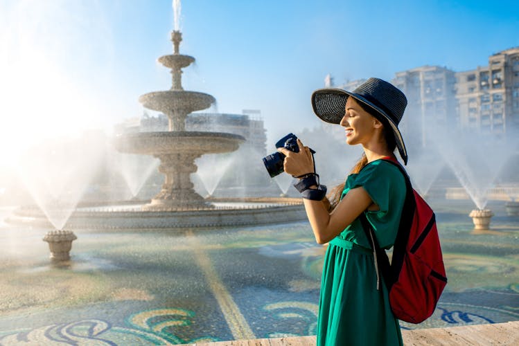 Young female traveler photographing central fountain in Bucharest city, Romania.
