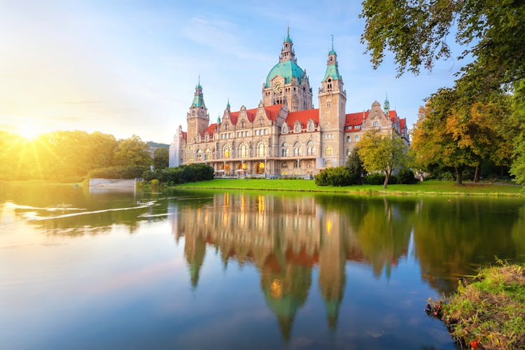 Photo of Hanover, Germany. Building of New Town Hall reflecting in water on sunset.
