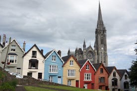 Photo of Colorful row houses with towering cathedral in background in the port town of Cobh, County Cork, Ireland.