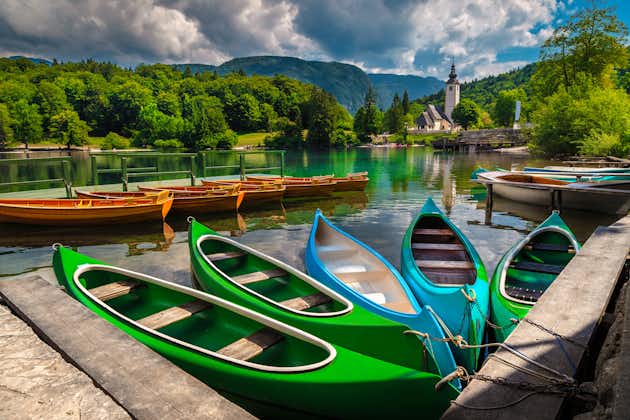 Anchored colorful canoes, kayaks and wooden boats on the lake. Leisure and sport objects on the lake Bohinj, Ribcev Laz, Slovenia, Europe