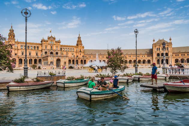 Photo of family in a rowing boat on the Plaza de España canal with imposing monument in the background.