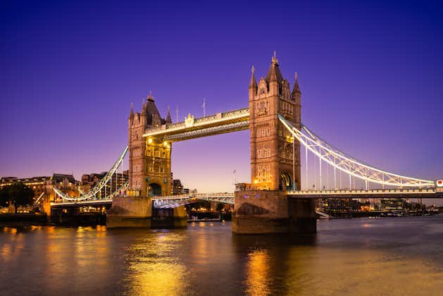 Photo of Tower Bridge illuminated at night by river thames in London, england, UK.