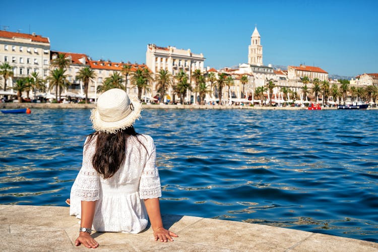 Photo of woman traveler enjoying the view of the beach and old town of Split in Dalmatia, Croatia.