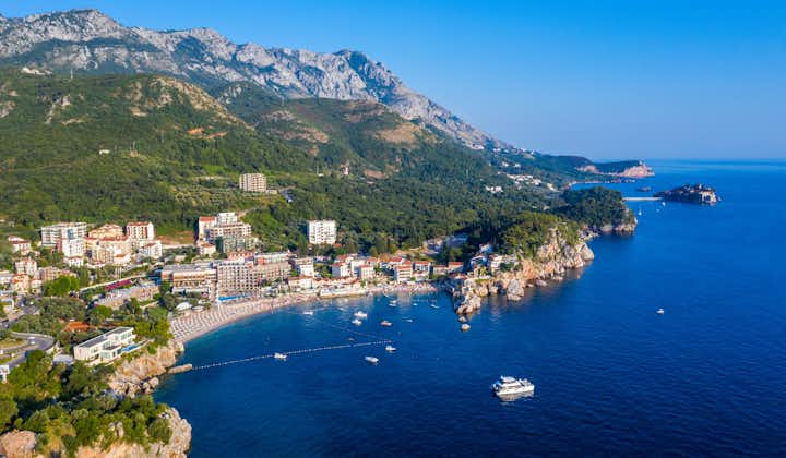 Panorama of the beach and the resort towns of Becici and Rafailovici, located at the foot of the mountains. Montenegro. Adriatic Sea. Summer sunny day. Seaside vacation concept.