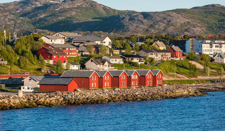 Photo of red houses facades reflecting on the bay of Alta, Norway.