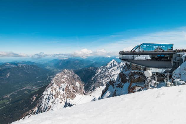 photo of at the top of Zugspitze, highest mountain of Germany, during summer with blue sky, snow and spectacular views to the valley (Zugspitze, Germany, Europe).