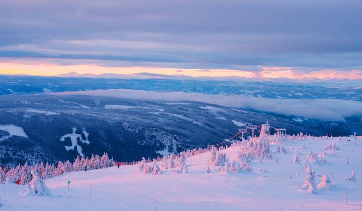 photo of an aerial view of ski resort Hafjell in Norway with skiers going down the snowy slopes in winter with mountains.