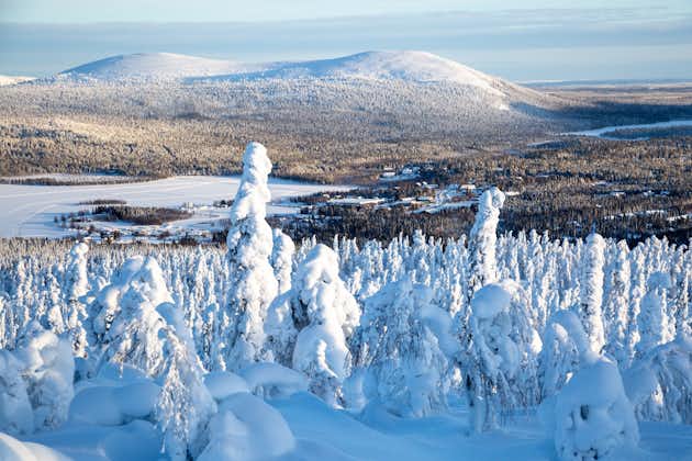 photo of snowy forest above the frozen lake and mountain background in Ylläs in Finland.