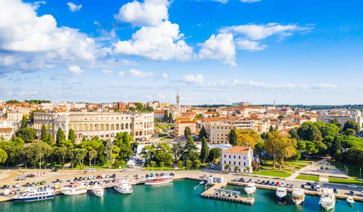 Photo of  city of Pula, ancient Roman arena, historic amphitheater and harbor with ships from drone, aerial view.