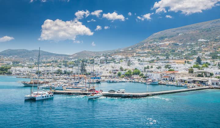 Photo of beautiful view of Parikia town in Cyclades Islands. There are white houses and boats in the old harbor.