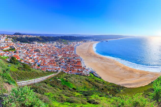 Photo of aerial view of Nazare beach riviera (Praia da Nazare) with cityscape of Nazare town in low season at sunny weather, Portugal.