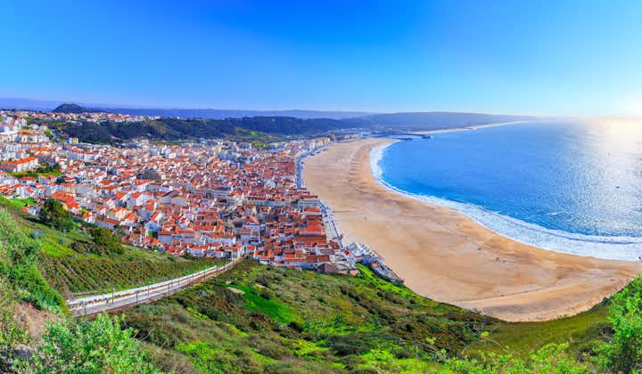 Photo of aerial view of Nazare beach riviera (Praia da Nazare) with cityscape of Nazare town in low season at sunny weather, Portugal.