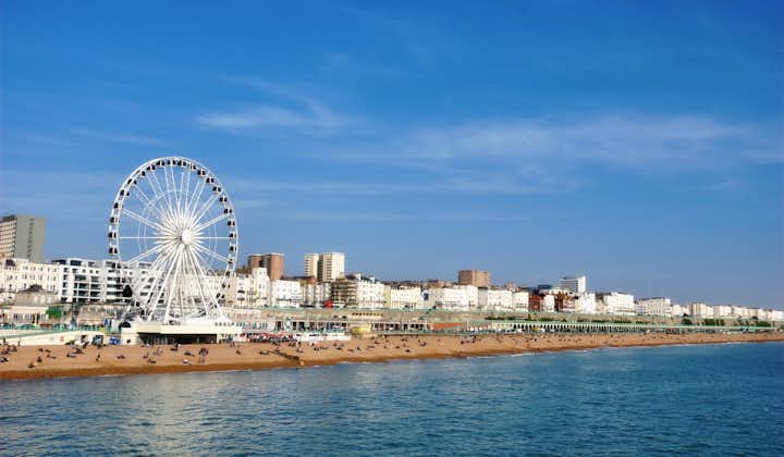 Photo of Brighton view of seaside from the pier with the famous ferris wheel, the stones beach with unrecognizable persons on a sunny summer day, United Kingdom.