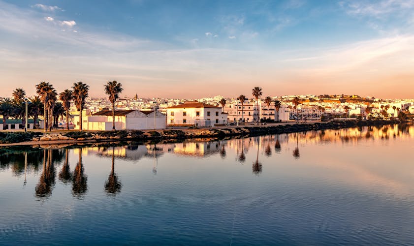 Photo of panoramic beautiful view of Conil de la Frontera in southern Spain at sunset, and town reflections on the calm waters.