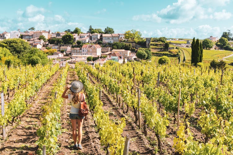 Photo of woman enjoying Saint Emilion village in green vineyard, Bordeaux in France.