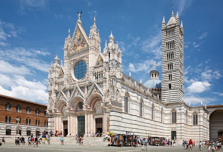 Photo of Siena cathedral against a bright blue sky in Italy.