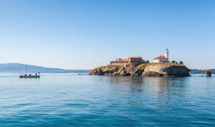 Photo of Saint Anastasia Island in Burgas bay, Black Sea, Bulgaria. Lighthouse tower and old wooden buildings on rocky coast.