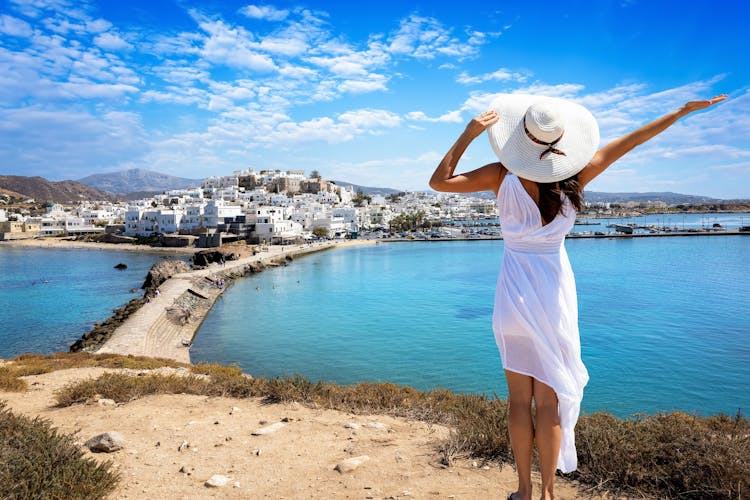 Photo of happy tourist woman looks at the beautiful town of Naxos island.
