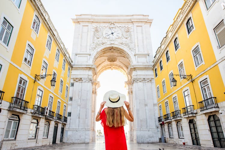 Photo of Young woman tourist standing back in front of the famous triumphal arch in Lisbon city center in Portugal.