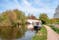 Photo of a narrow boat moored at the river Gade, Grand Union Canal. The Grove Bridge aka Grove Ornamental Bridge No 164 is in the background, Cassiobury Park, Watford, England.