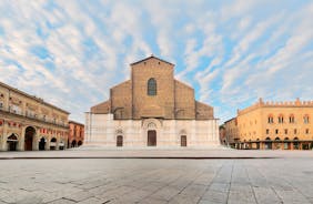 Photo of Italy Piazza Maggiore in Bologna old town tower of town hall with big clock and blue sky on background, antique buildings terracotta galleries.