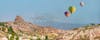 photo of hot air balloon flying over spectacular Uchisar castle and Pigeon valley in Cappadocia, Turkey.
