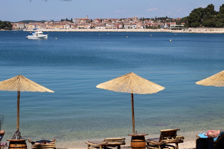 Photo of sunshades and sunbeds on a Golden Cape park beach with a view of Rovinj, Croatia.
