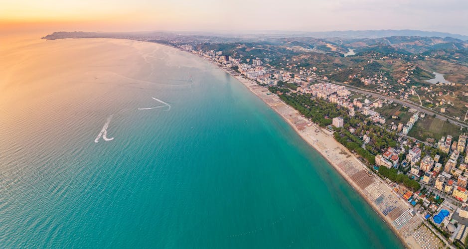 Photo of aerial view of the beautiful coastline with sandy beach of the Albanian town of Golem with the city of Durres in the background.