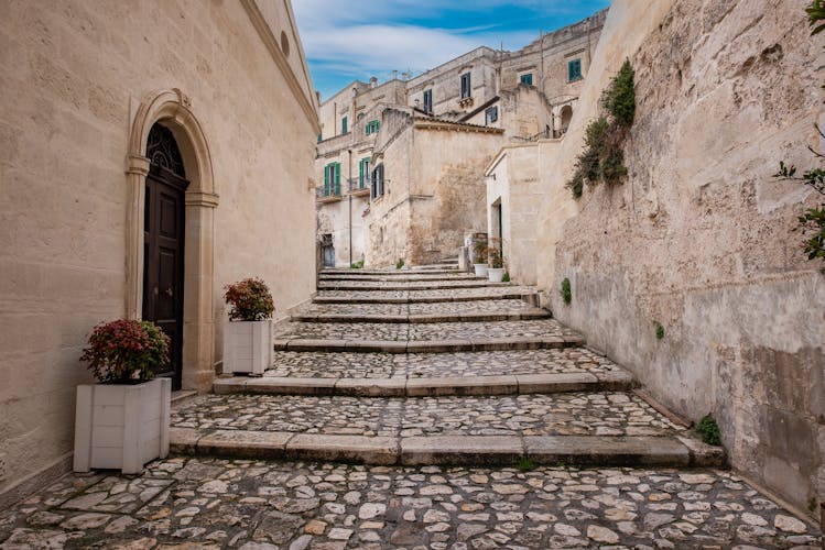 Photo of buildings in the old town of Matera, Basilicata, Southern Italy with blue sky and white clouds.