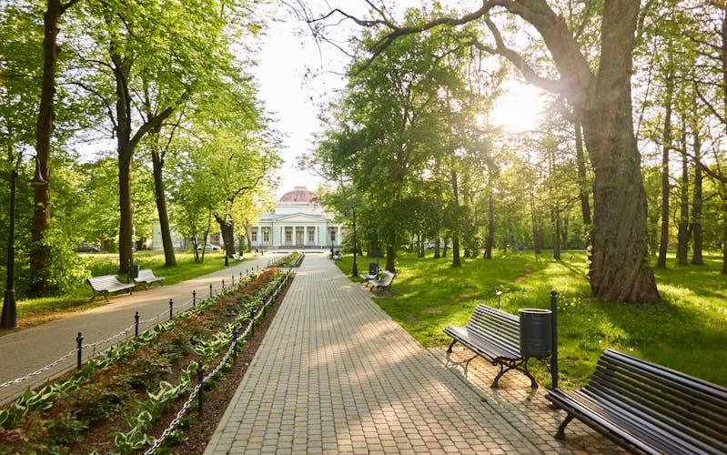photo of view of Alley in city park. Benches, floral decoration, bicycle road, trees, flowers, plants. Liepaja, Latvia. Summer landscape. Public places, urban planning, landscaping design, gardening, recreation themes