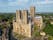 Photo of aerial view of Lincoln cathedral in morning light with stunning towers large medieval architecture west face sitting on hill overlooking historic city.