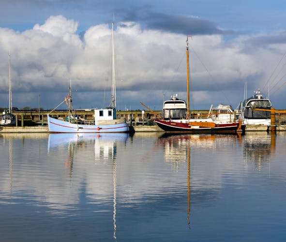 photo of view of Colorful fishing boats with reflections in the calm waters of the fishing harbor of Lemvig, Denmark.