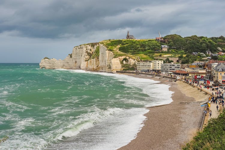 Panoramic view to white Étretat rock Falaise d'Amont. Steep vertical chalk cliff with a natural arch, and beach below, washed by the stormy Atlantic Ocean. Alabaster Coast, Normandy, France.