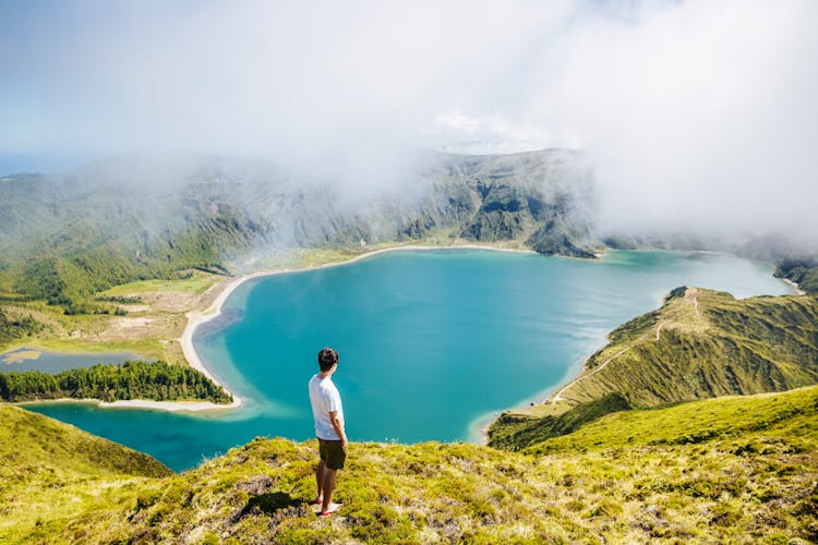 Photo of tourist looking at beautiful Lagoa do Fogo lake in Sao Miguel Island, Azores, Portugal. 
