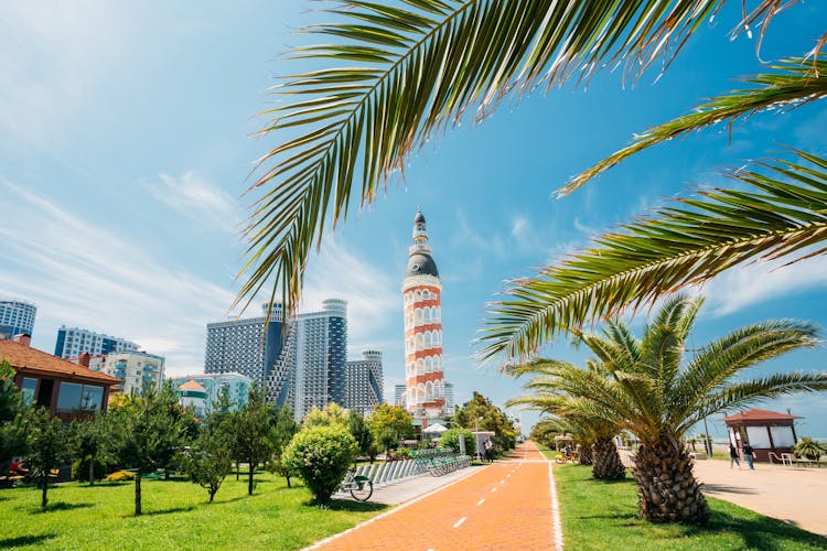 Photo of old Tower And Modern Skyscraper Residential House On Blue Sky Background In Batumi.