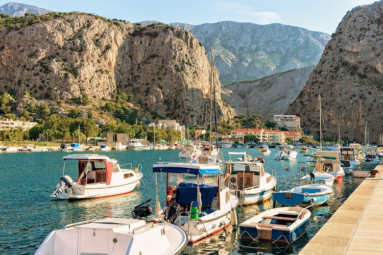 Photo of fishing and sailing boats on the Cetina river in Omis resort. Anchored boats and high mountains in background, Omis, Makarska riviera, Dalmatia, Croatia.