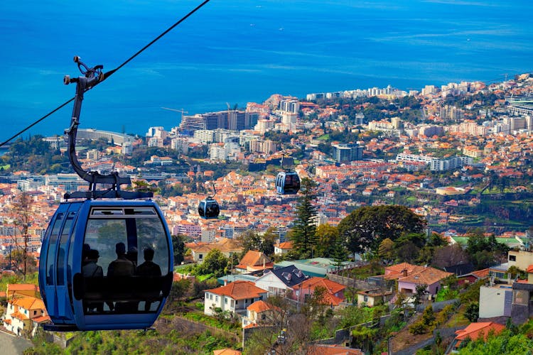 Photo of erial view of Funchal with traditional cable car above the city.