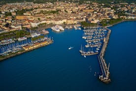 Photo of Old harbour Porto Vecchio with motor boats on turquoise water, green trees and traditional buildings in historical centre of Desenzano del Garda town, Northern Italy.