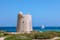 photo of beautiful views of the old observation tower (Torre de Ses Portes) and the sailing yacht in front of the island of Ibiza, Spain.