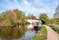Photo of narrow boat moored at the river Gade, Grand Union Canal. The Grove Bridge aka Grove Ornamental Bridge No 164 is in the background in Cassiobury Park, Watford, England.