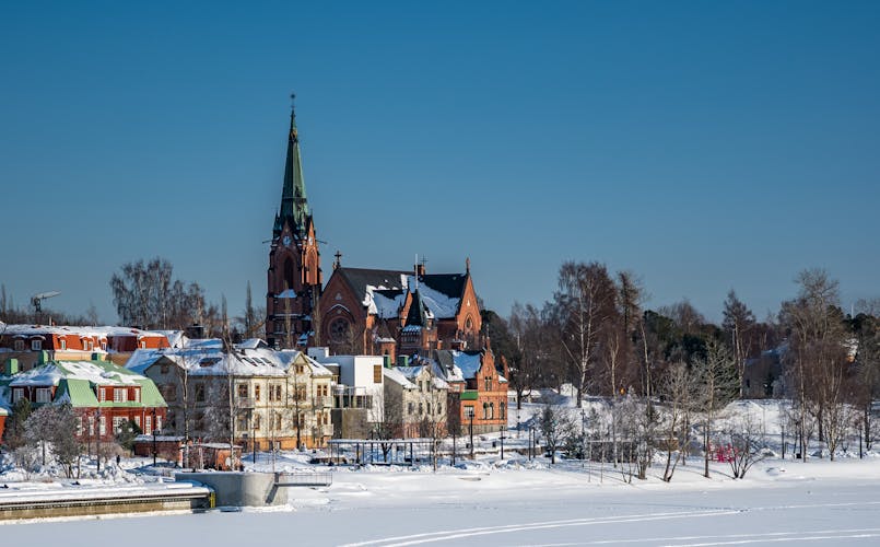 Umea City Church in winter overcast, many old buildings at frozen river coast, blue clear sky, Sweden.