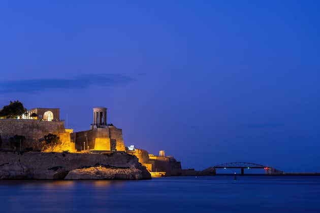 Nightscape in Malta, Siege Bell War Memorial and St Elmo Bridge at night on seaward shore of the Sciberras Peninsula in the Mediterranean Sea.