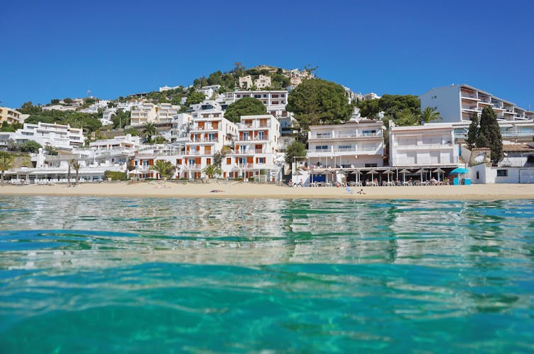 Photo of Spain Costa brava beautiful beach with buildings waterfront, Mediterranean, seen from sea surface, Roses.