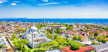 Touristic sightseeing ships in Golden Horn bay of Istanbul and mosque with Sultanahmet district against blue sky and clouds. Istanbul, Turkey during sunny summer day.