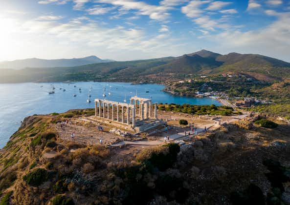Photo of aerial view of the beach and Temple of Poseidon at Cape Sounion at the edge of Attica, Greece, during summer sunset time.