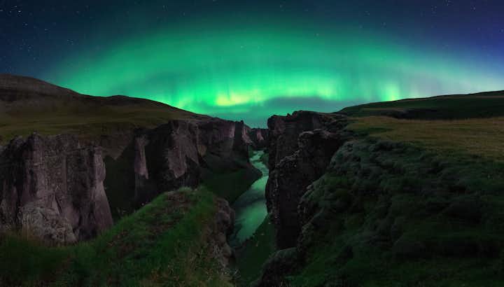 photo of fjaðrárgljúfur canyon at night, with northern lights in Iceland.
