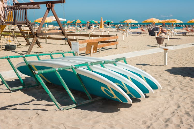Photo of Surfboard on sandy beach at beach Viserbella Italy on background of beach umbrellas and sunbeds.